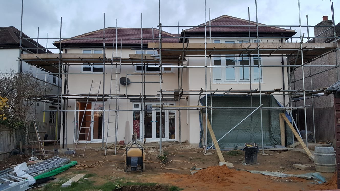 Rear of a two-storey house under scaffolding while an extension is built